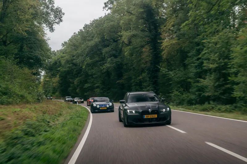 Cars driving in convoy on a tree-lined road