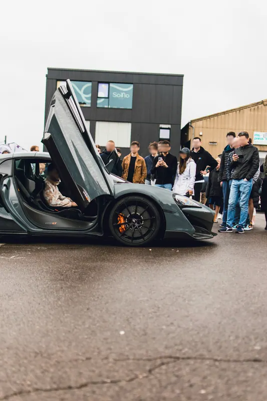 Visitors beside a supercar with its door open